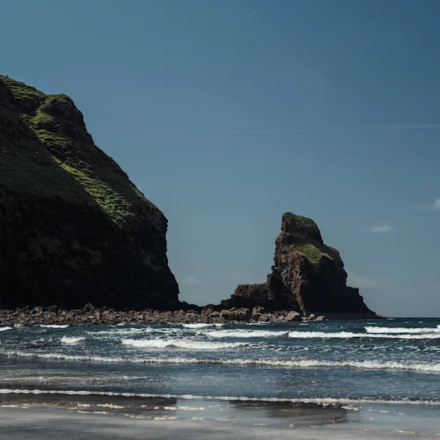 A beach with large rocks on the horizon