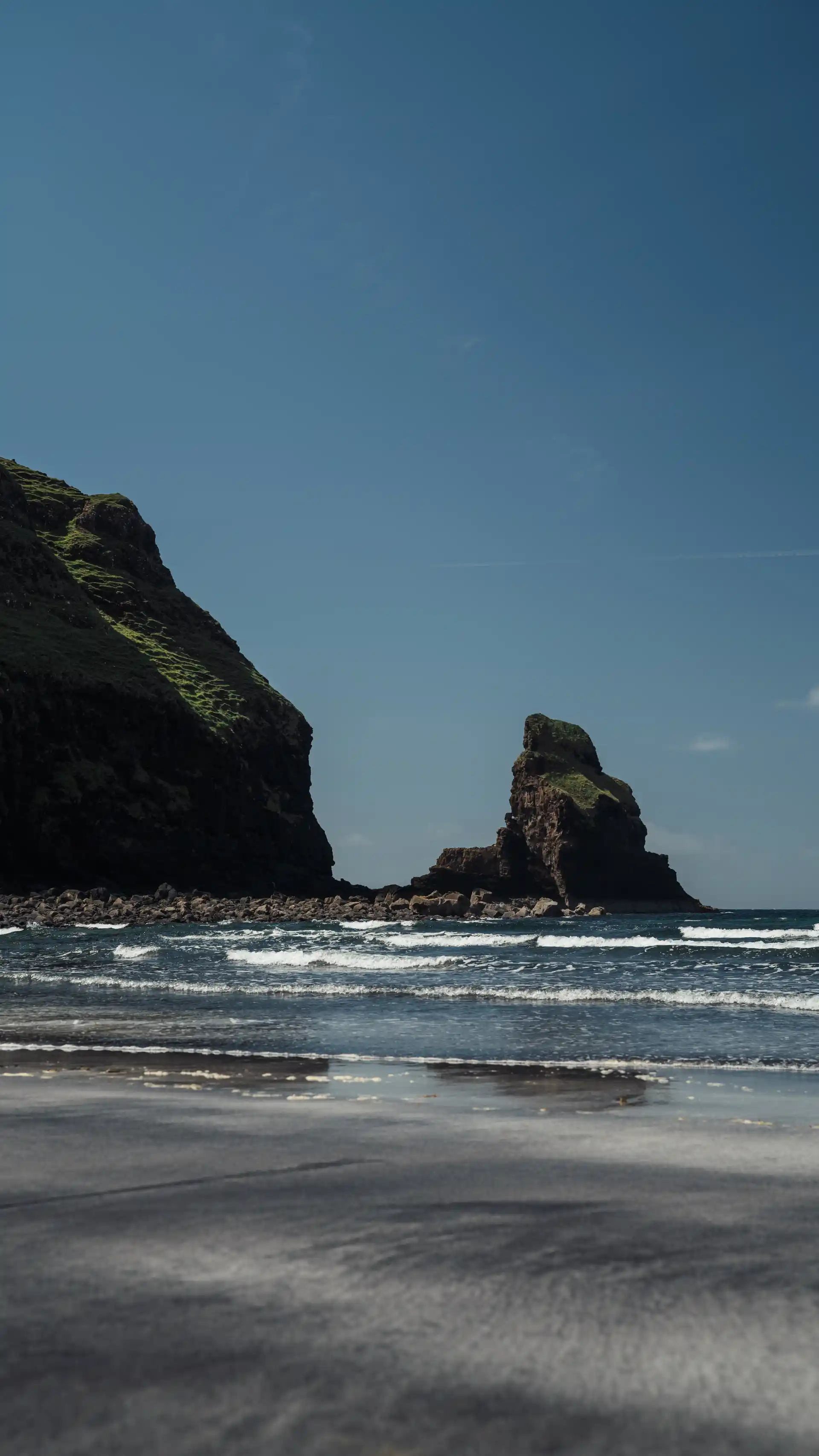 Een strand met grote rotsen aan de horizon