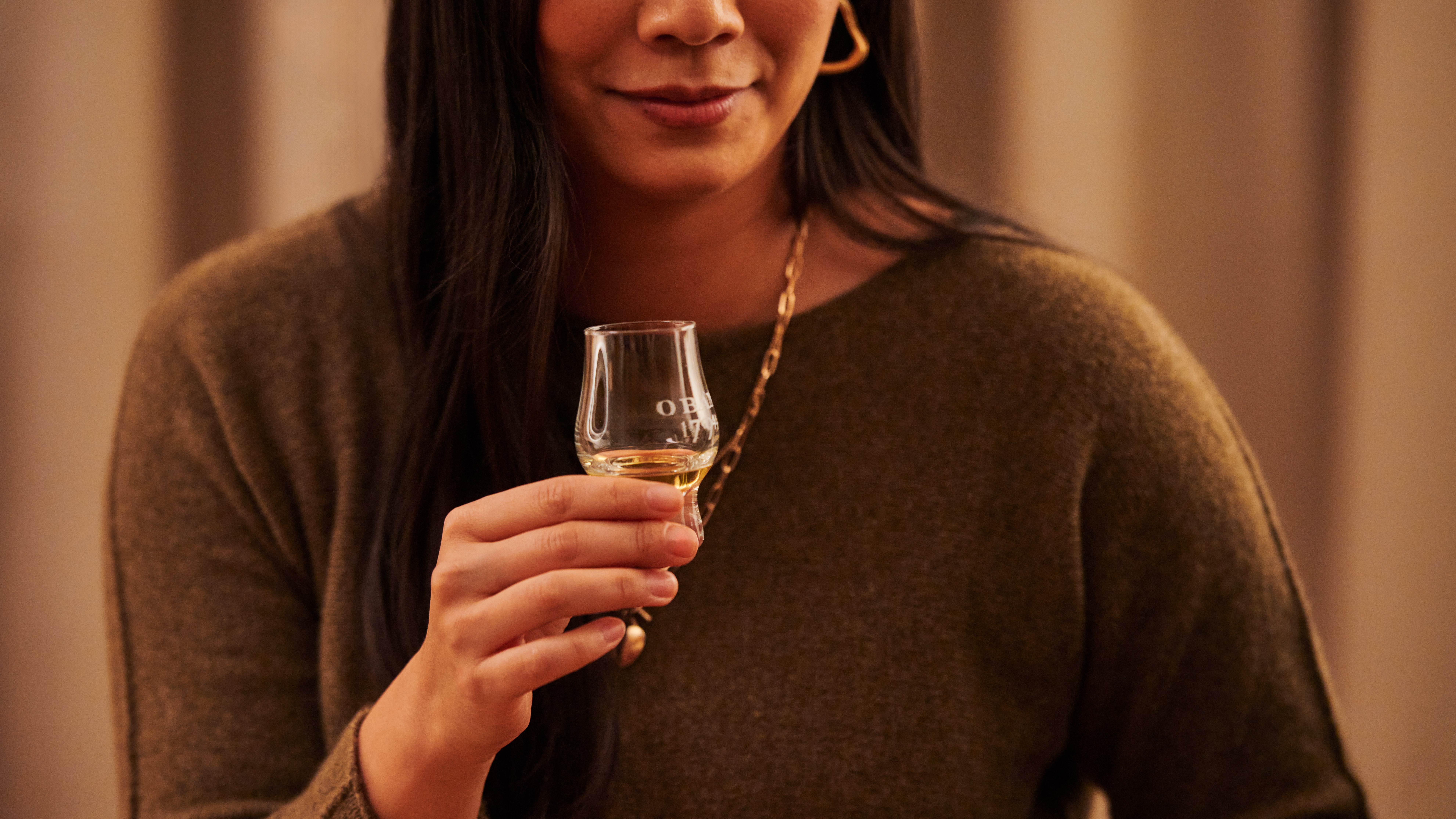 Een vrouw houdt een klein whisky proefglas vast met het woord Oban erop gedrukt