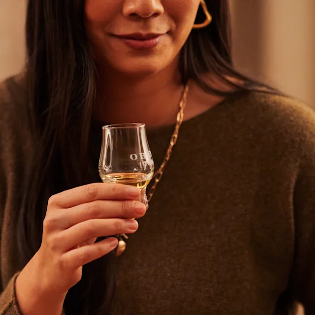 Eine Frau hält ein kleines Whisky-Verkostungsglas mit dem Aufdruck "Oban