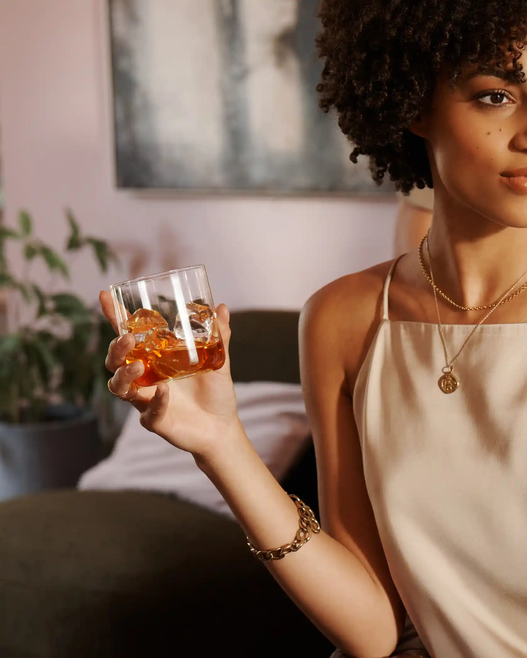 A woman holds a rocks glass of whisky and ice