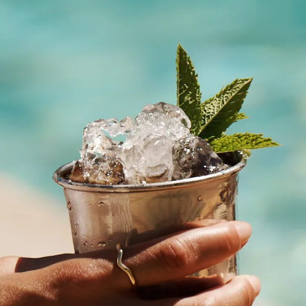 Mint Julep Cocktail in tankard being held by the pool