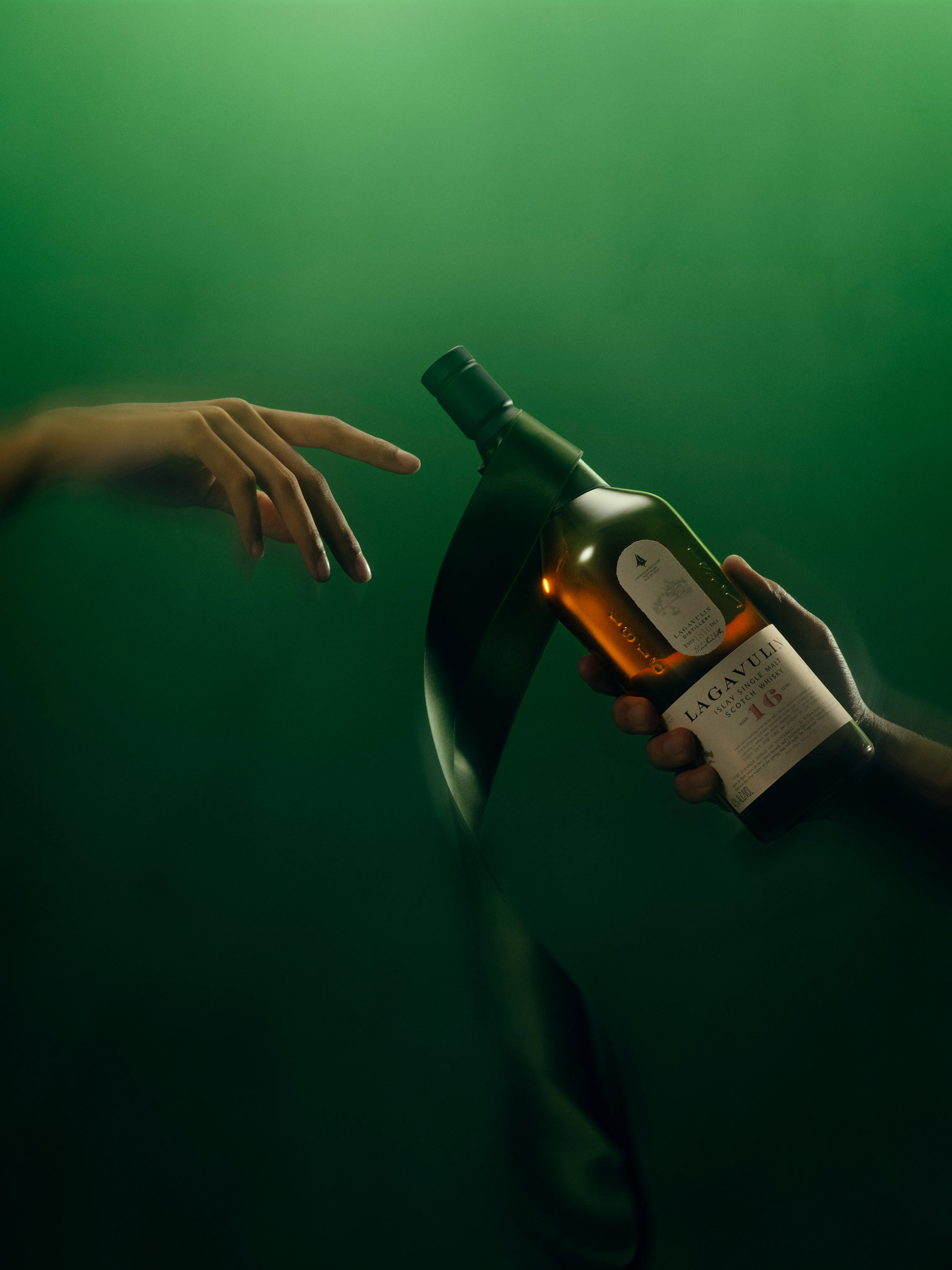 Finger reaching out to touch Lagavulin bottle 
