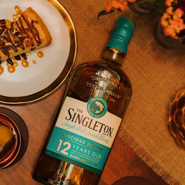 A bottle of The Singleton 12-year-old single malt Scotch whisky placed on a table next to a dessert platter.