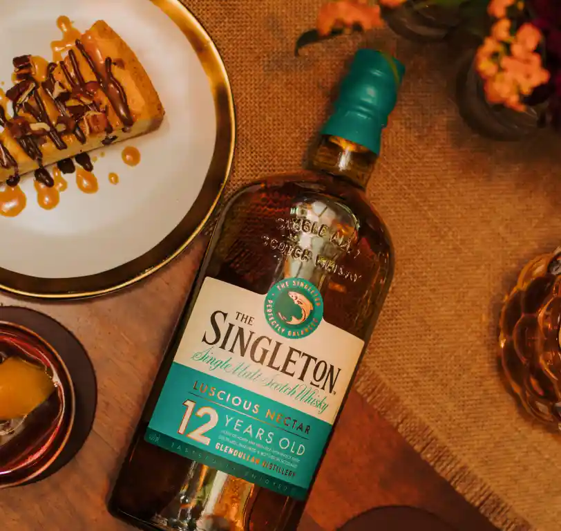  Eine Flasche des 12 Jahre alten Single Malt Scotch Whiskys von The Singleton steht auf einem Tisch neben einem Dessertteller.