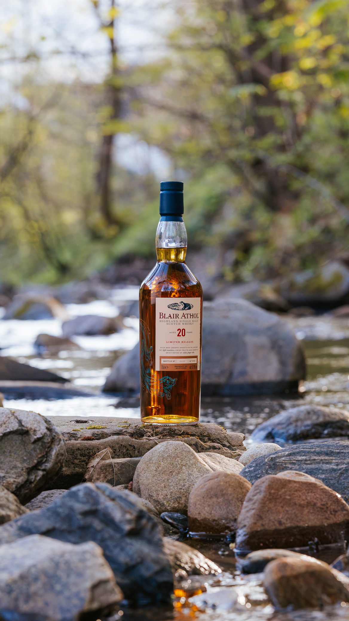 A bottle of Blair Athol on a rock near a creek