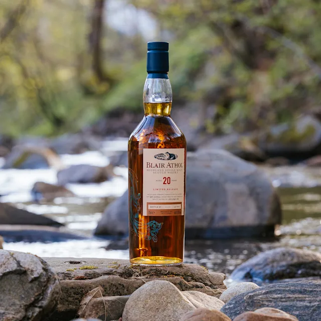A bottle of Blair Athol on a rock near a creek