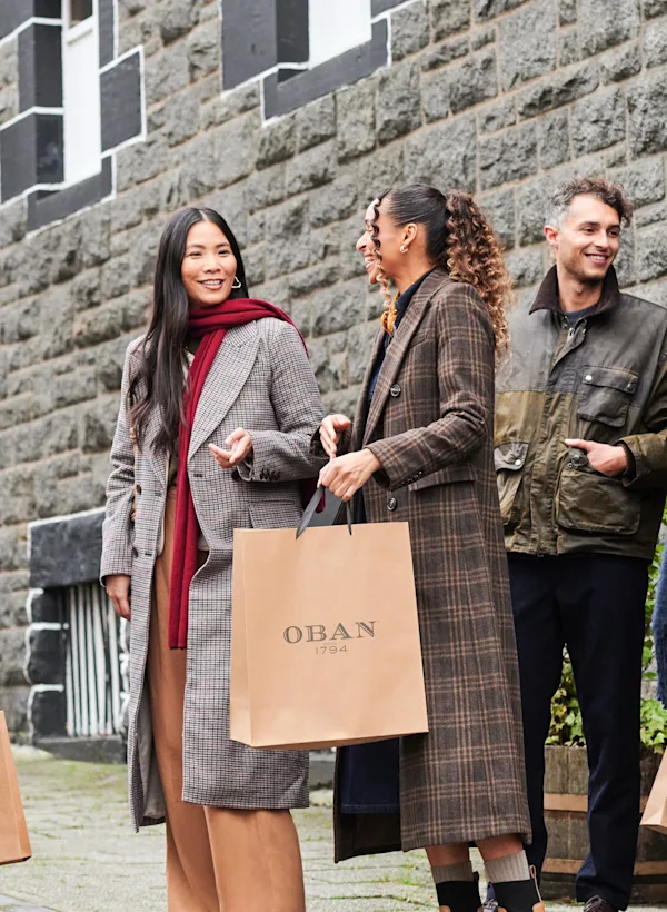 A group of friends leave Oban distillery holding brown gift bags