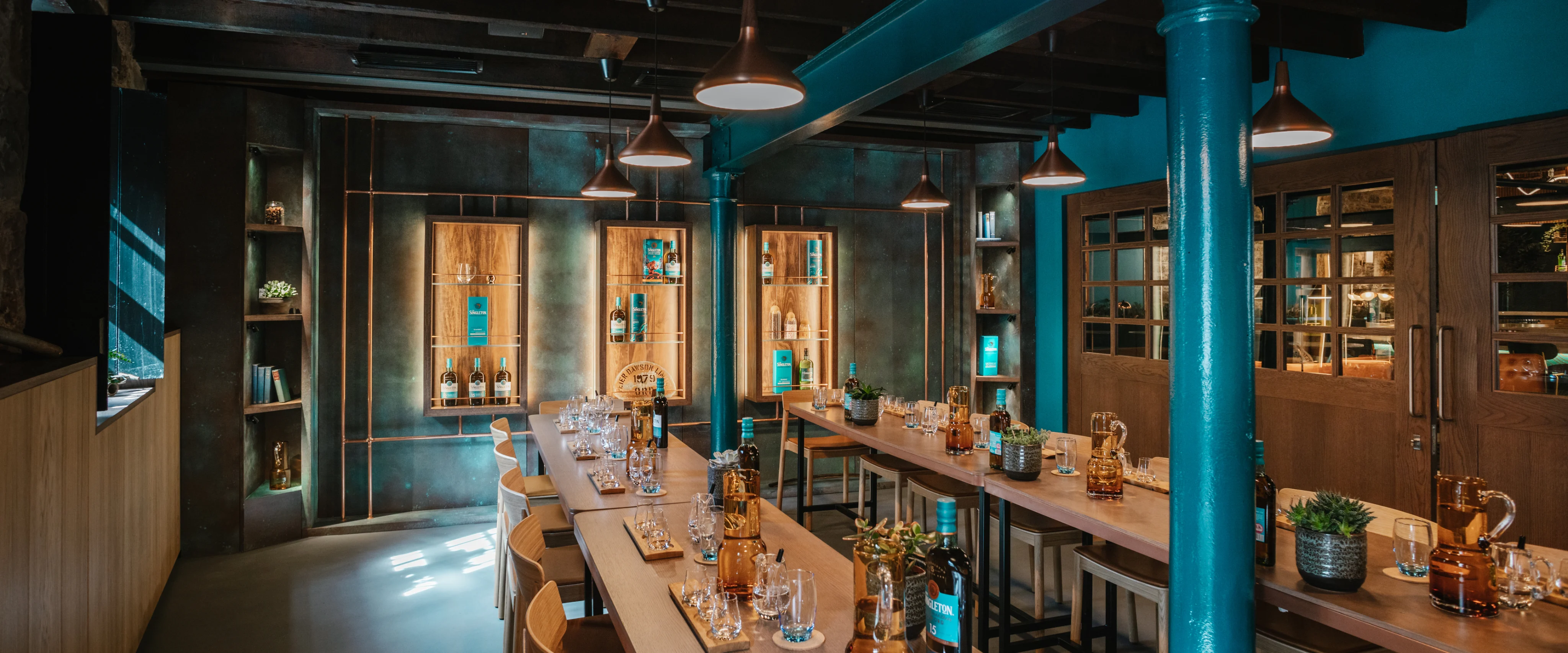 Interior of The Singleton of Glen Ord Distillery visitor center with tasting tables and copper stills.
