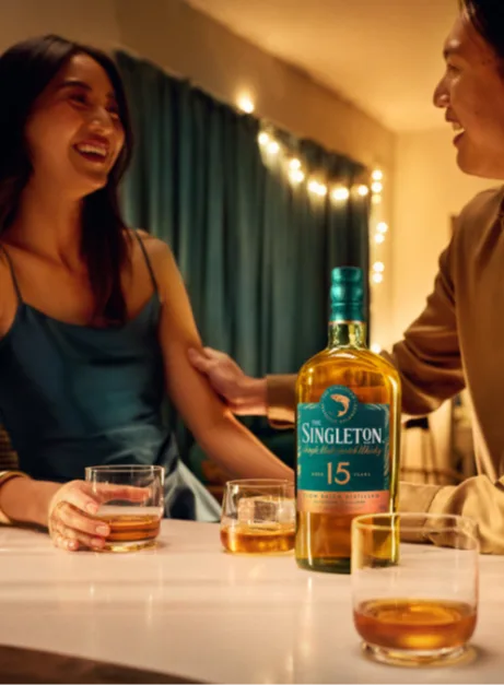 Friends laugh over glasses of whisky and a bottle of The Singleton 15 Year Old