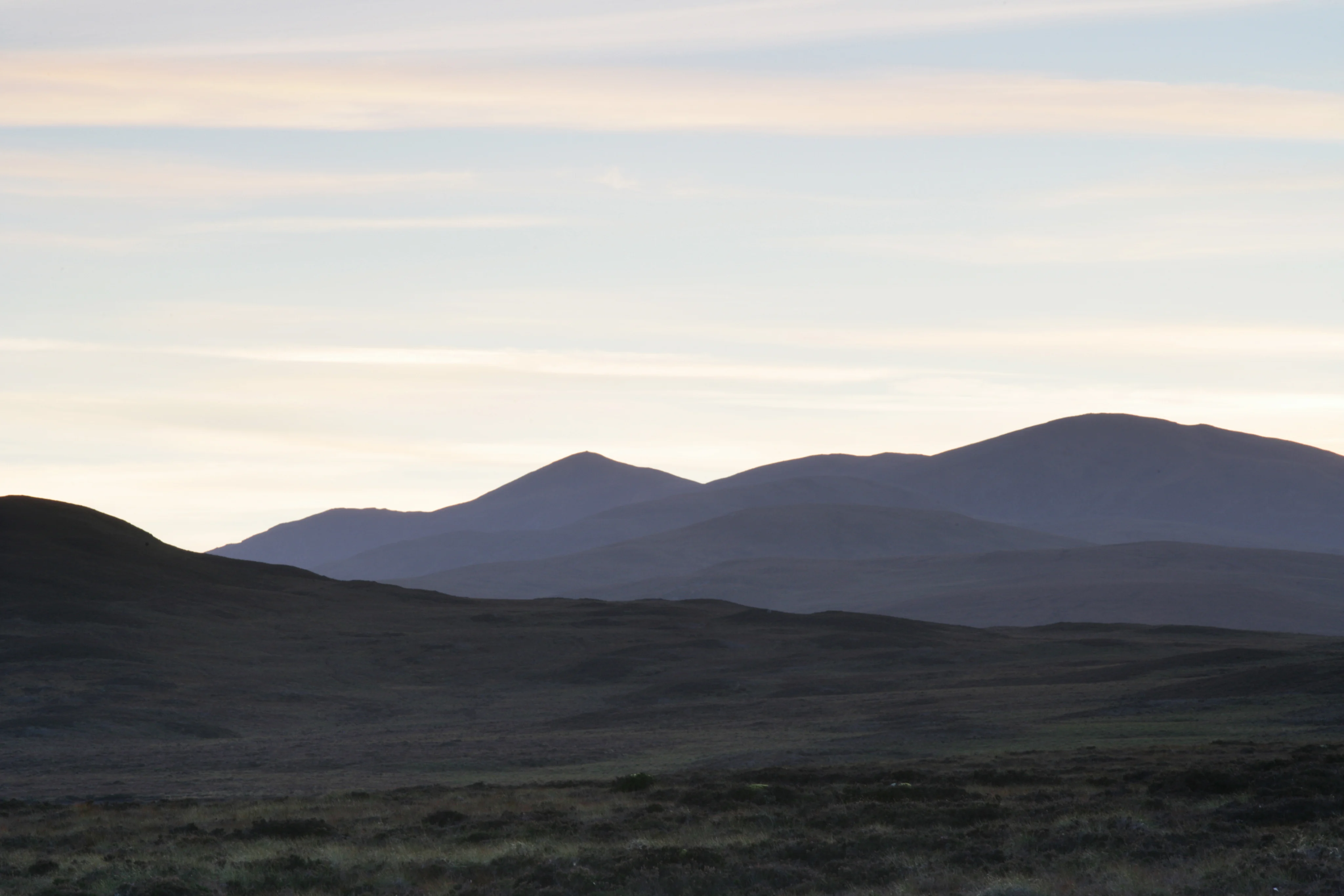 Scenic view of the Scottish Highlands with rolling hills and soft evening light.