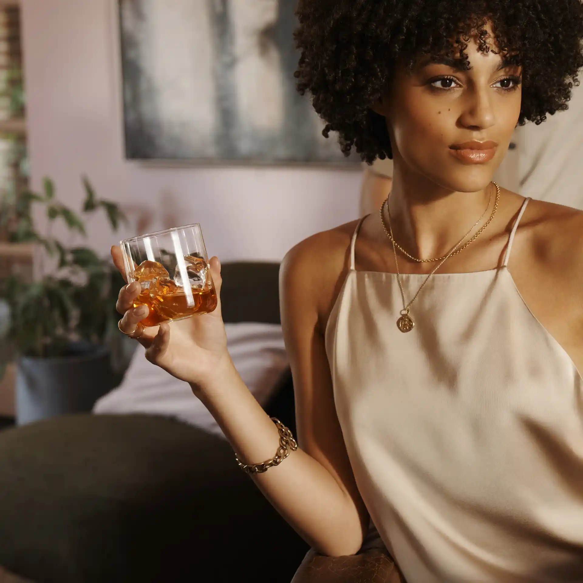 A woman holds a rocks glass containing whisky and ice.