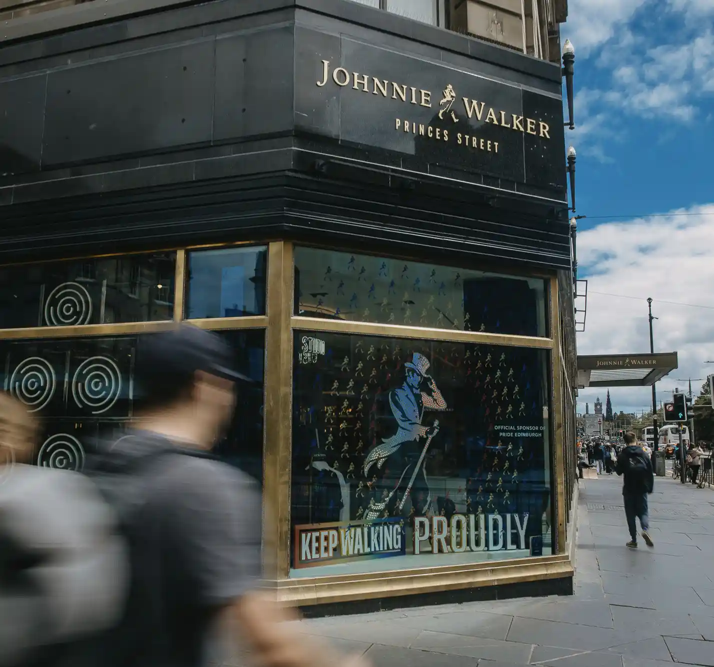 Ein Mitarbeiter von Johnnie Walker steht auf einer Bühne und spricht zu einer Gruppe von Menschen, die davor sitzen. Der Mitarbeiter deutet auf die Leinwand hinter ihnen, auf der eine Projektion mehrerer Holzfässer zu sehen ist.