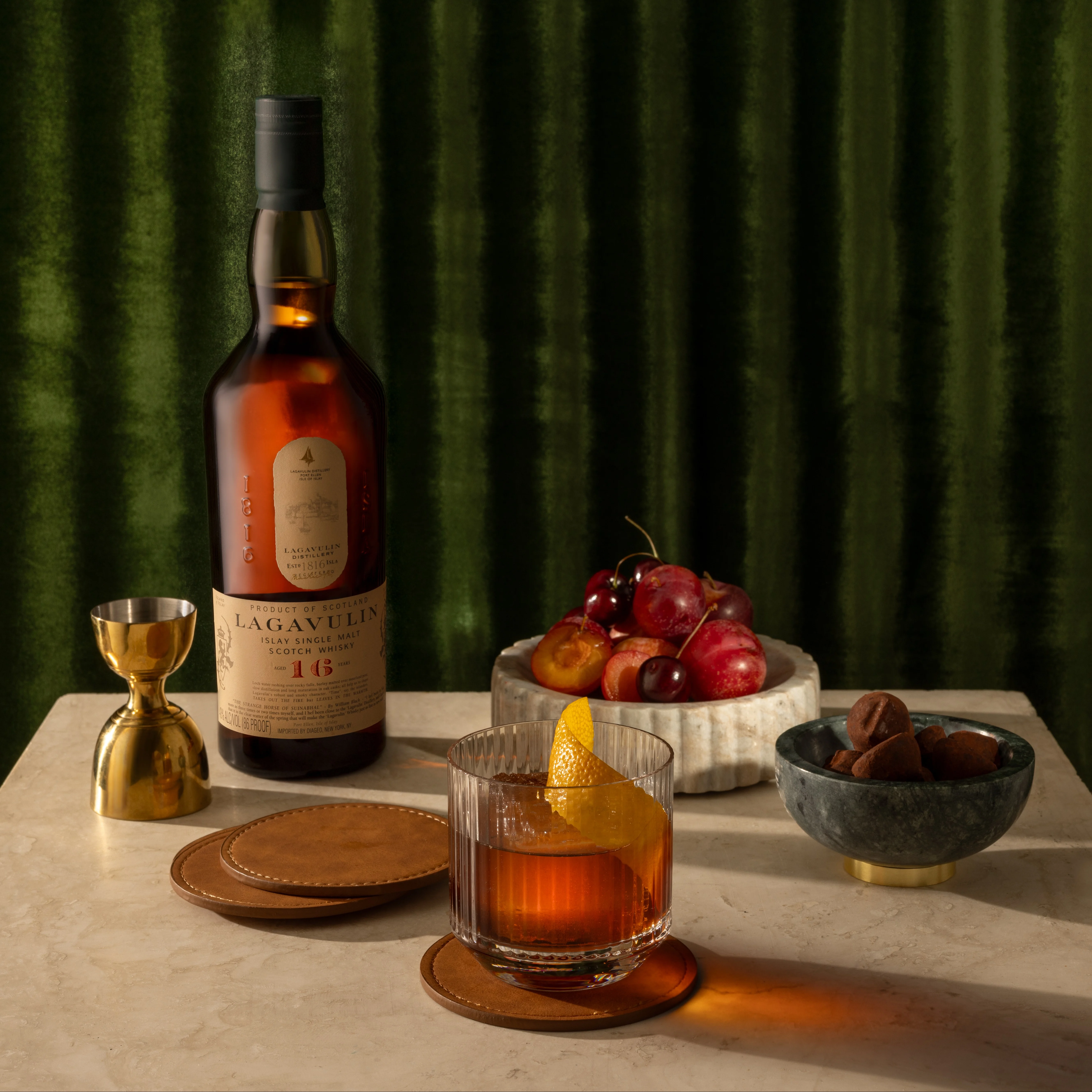 A cocktail in a rocks glass with a large twisted orange peel garnish