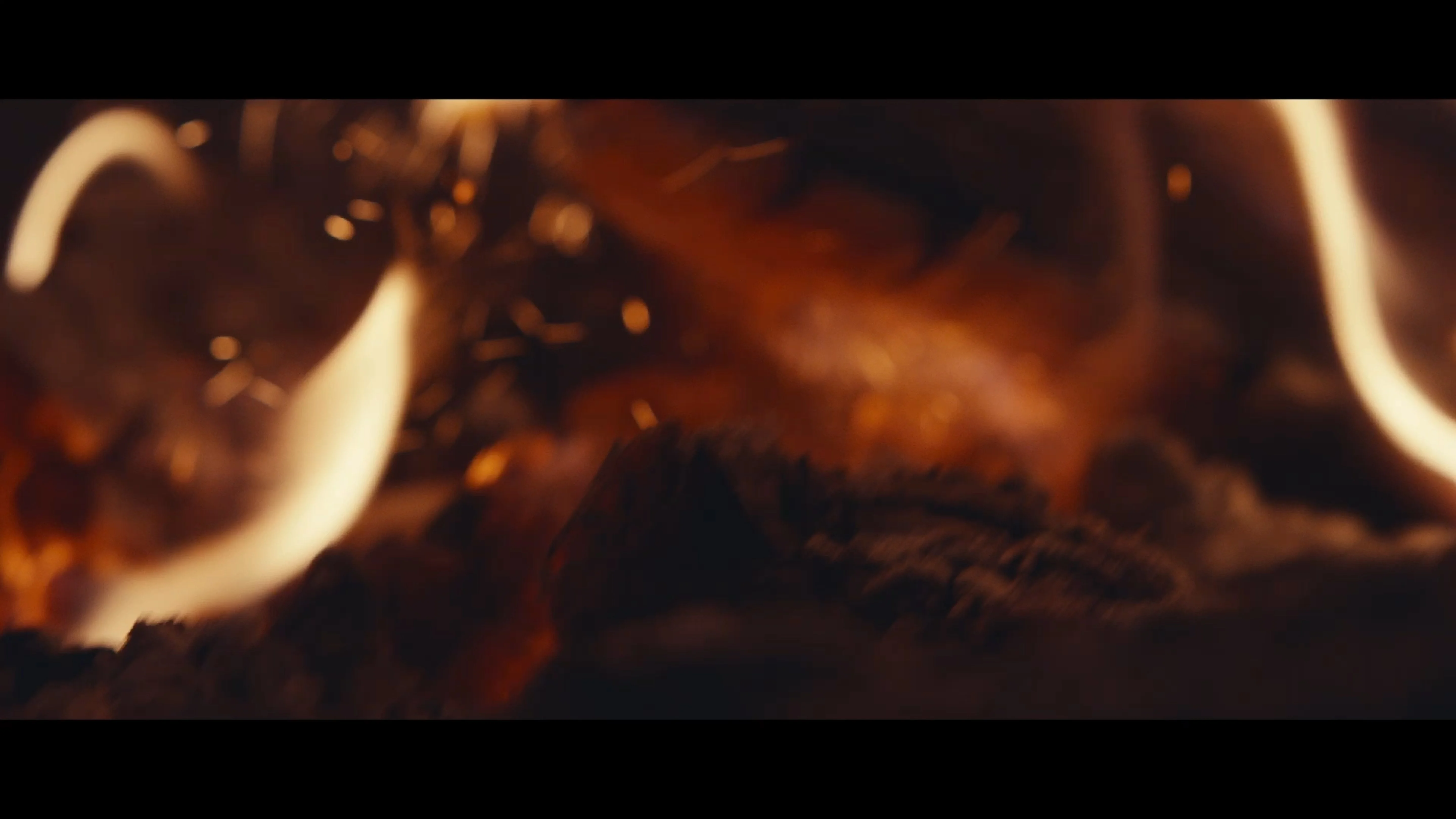 Die weißen Gebäude der Talisker-Brennerei sind von einem Gewässer aus zu sehen, umgeben von üppig grünen Hügeln und Bäumen. Der Schriftzug "Talisker" ist in schwarzen Buchstaben an einem Gebäude angebracht.