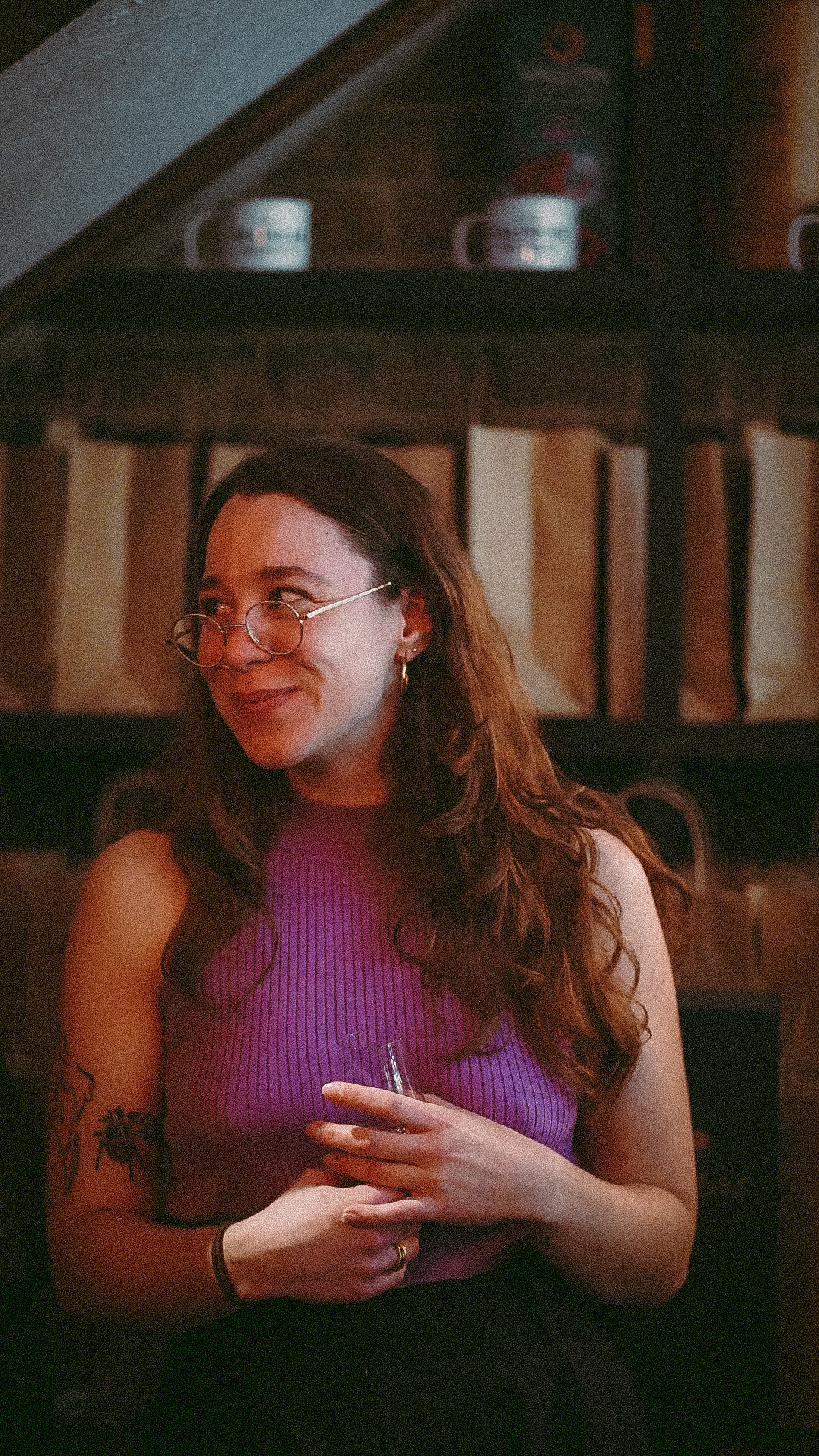 Charlotte Barker steht mit einem Glas in der Hand vor der Kamera und lächelt.