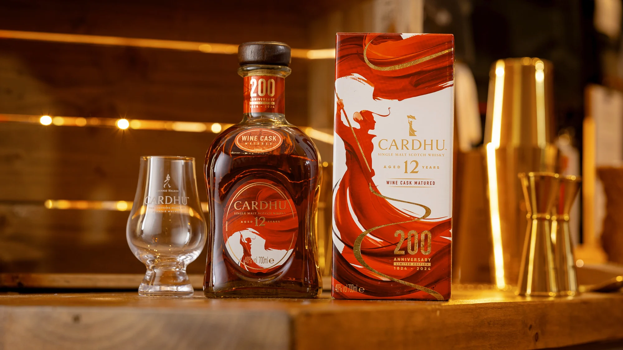 A bottle of 12 year old Cardhu Single Malt Scotch Whisky sits on a wooden table surrounded by a Cardhu branded glass and the packaging for this limited edition bottle.