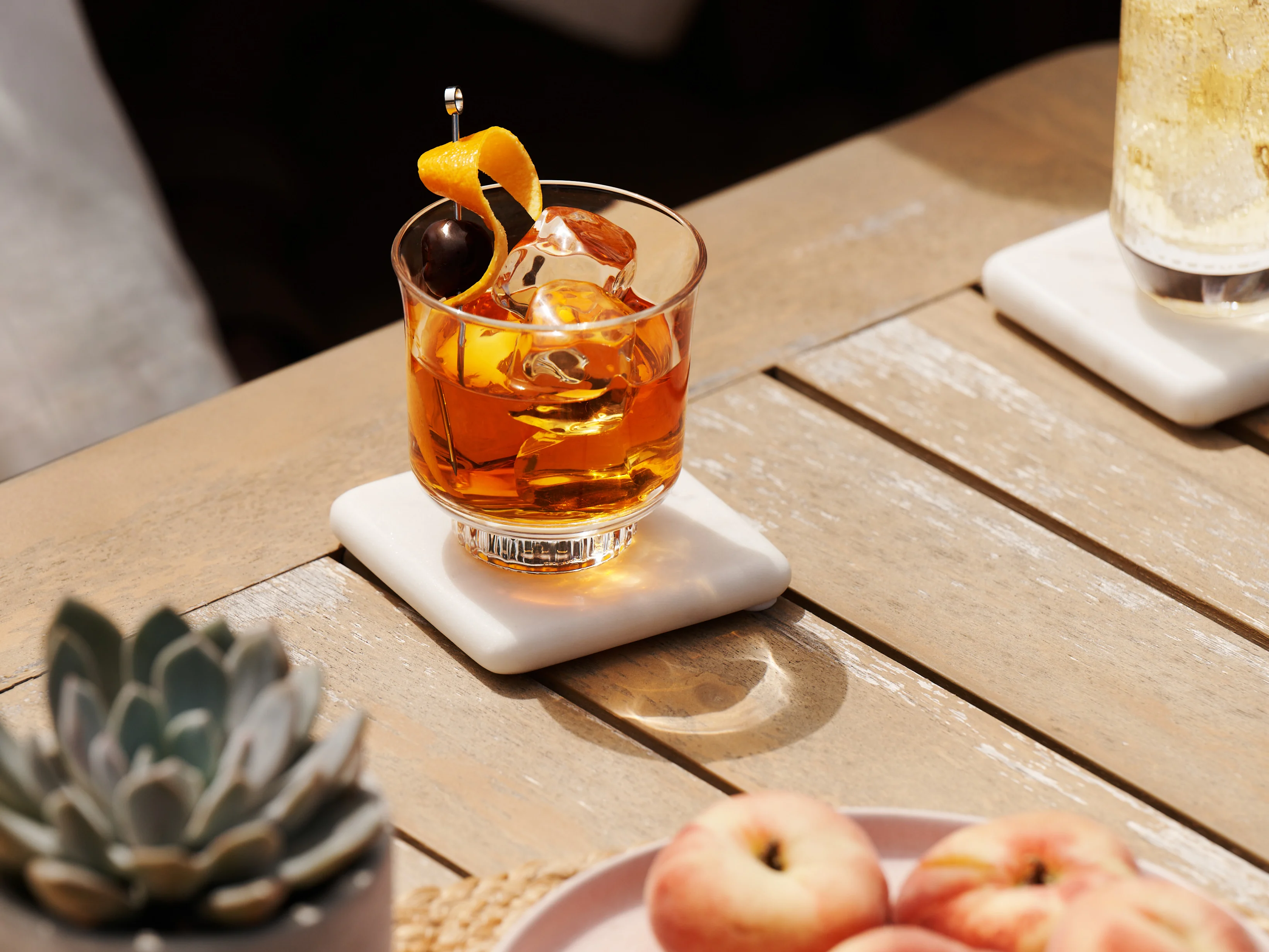 Een Old Fashioned-whiskycocktail in een rocksglas, gegarneerd met een gedraaide sinaasappelschil en een maraschino-kers