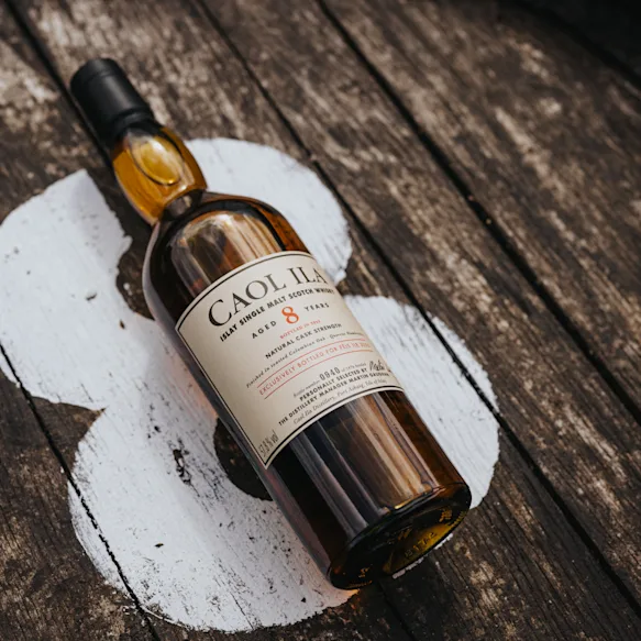 Caol Ila 8 Year Old Fèis Ìle 2025 Edition bottle lying on a wooden barrel painted with a white number 8.