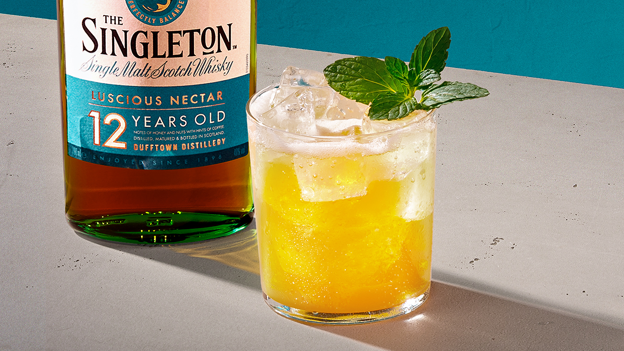 Ein Glas mit einem gelben Whisky-Cocktail neben einer Flasche The Singleton 12 Jahre Single Malt Scotch Whisky.