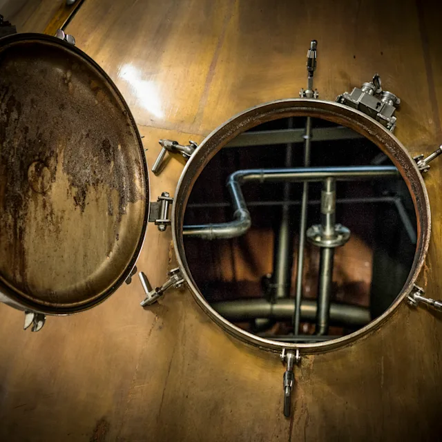 The inside of a whisky still is shown through its open hatch