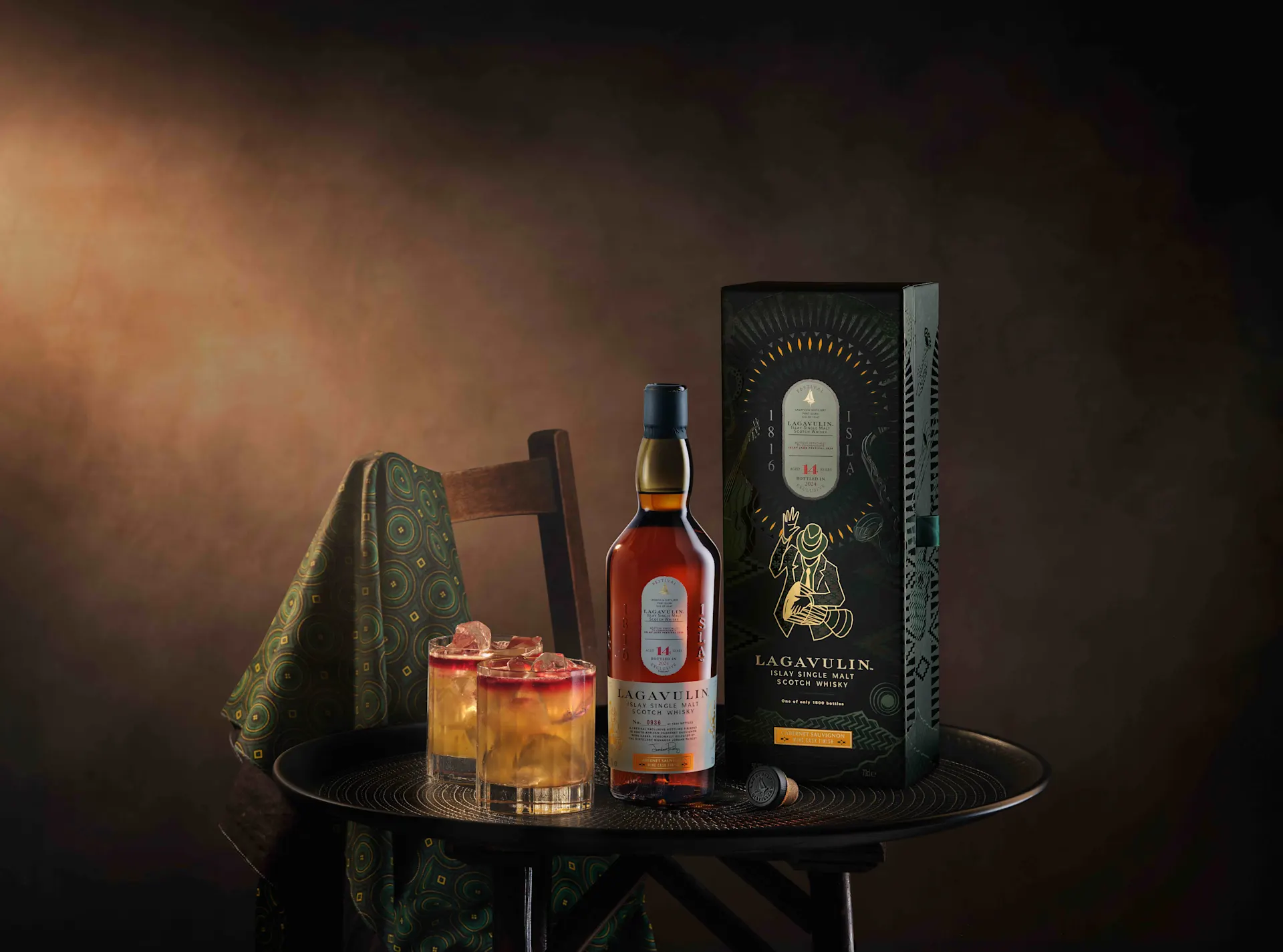 Bottle of the new Lagavulin Jazz Festival 2024 special edition on top of a table beside the whisky box and two lovely cocktails