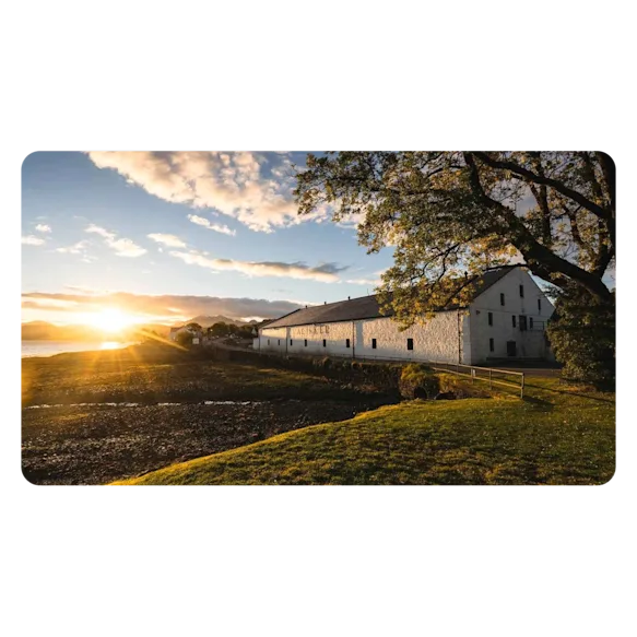 The sun shines across the beautiful landscape illuminating the white building that is home to Talisker.