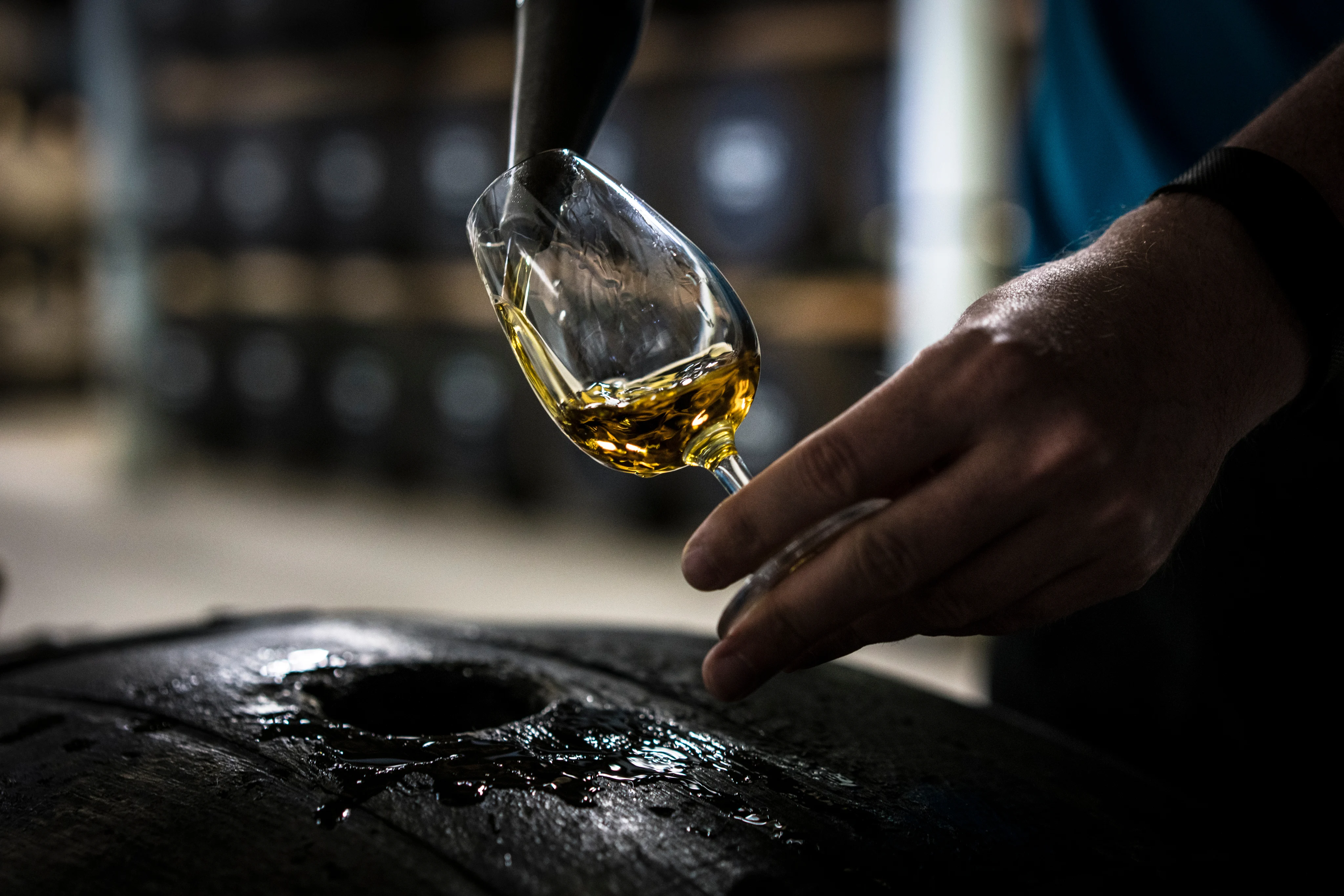 Close-up of whisky being poured into a tasting glass at a distillery.