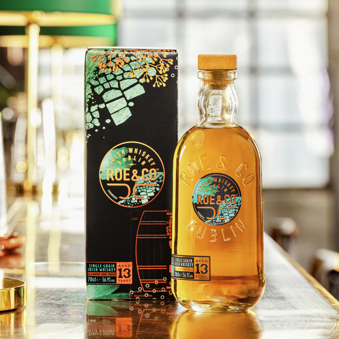Roe & Co 13-Year-Old Cask Strength Irish Whiskey bottle placed next to its packaging box, displayed on a bar surface with warm, ambient lighting.