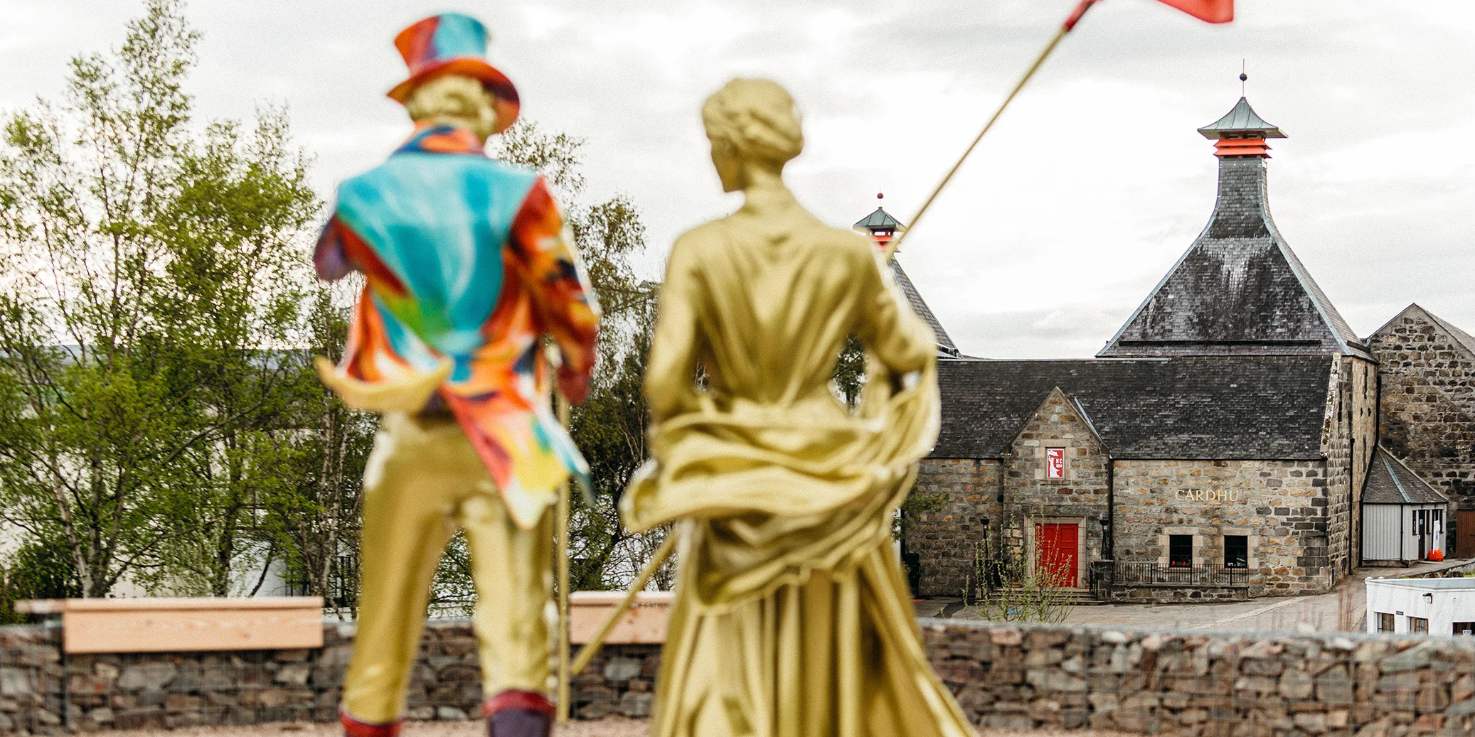 Two gold statues of a Victorian couple outside Cardhu distillery in Speyside