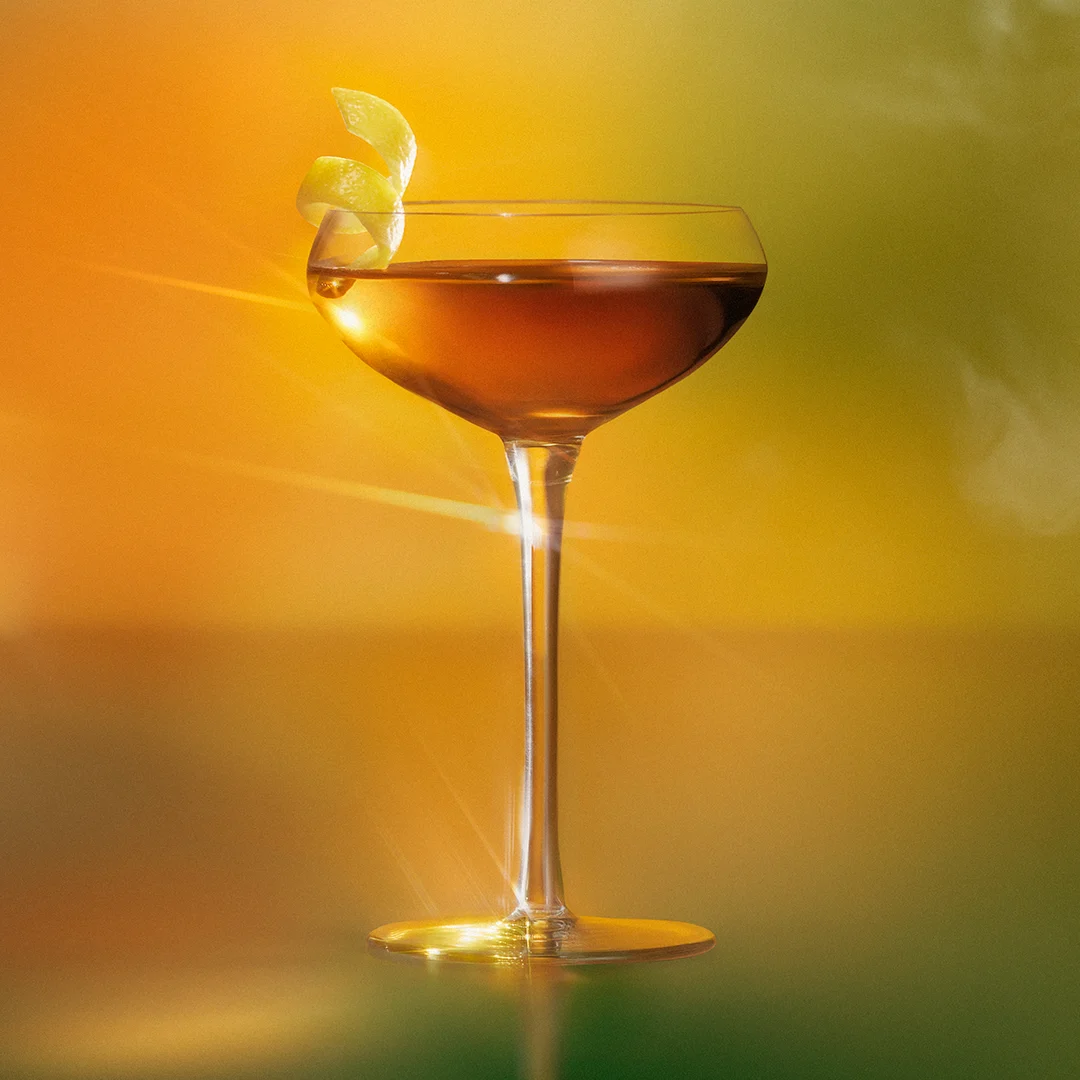 A cocktail in a coupe glass with a spiral lemon peel garnish