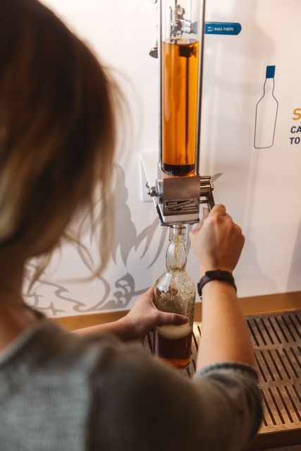 A person uses the Talisker fill your own bottling tap to fill a bottle with whisky