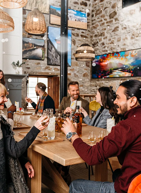 Group of happy visitors sitting around a rectangular table at Cardhu Distillery doing a tasting experience