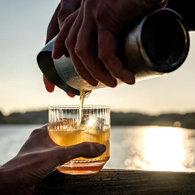 Pouring a drink into a whisky tumbler overlooking the Lagavulin Bay