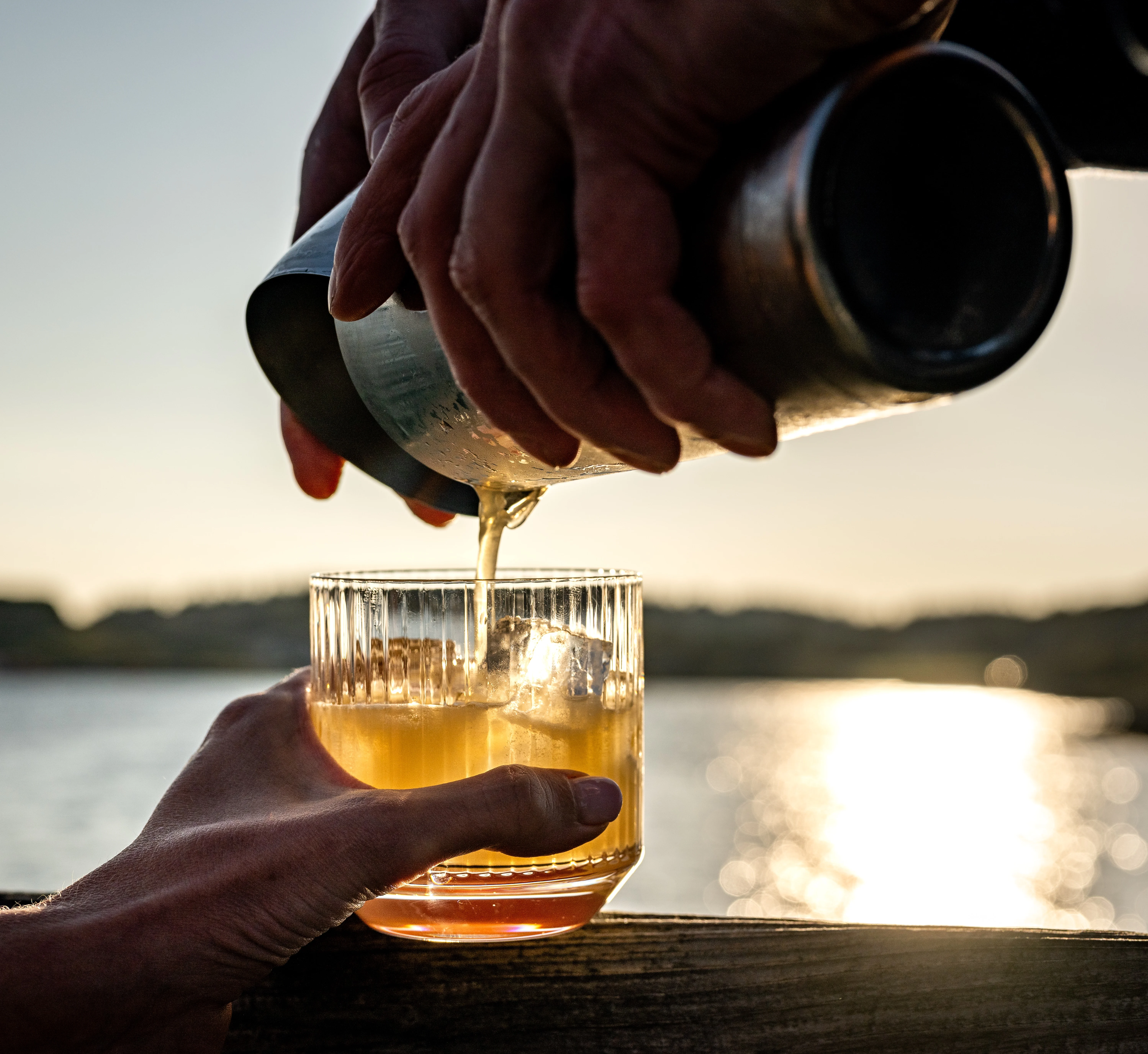 Einschenken eines Getränks in einen Whisky-Tumbler mit Blick auf die Lagavulin-Bucht