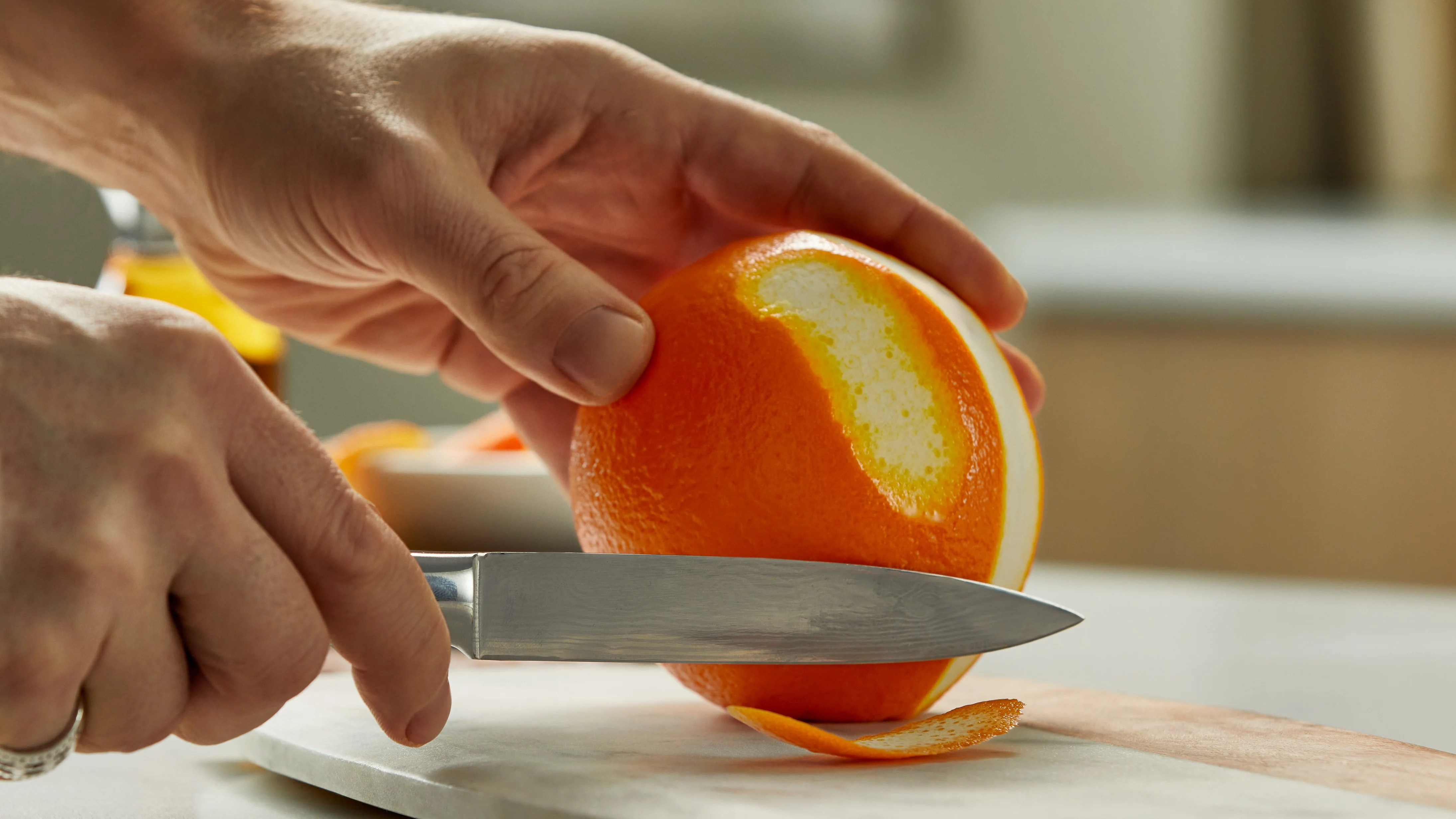 Eine Person schneidet eine Orangenschale