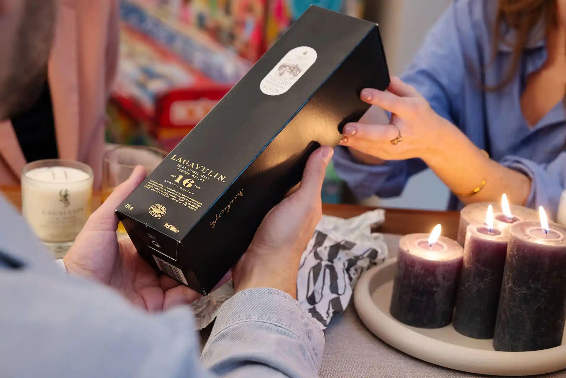 A small and comfortable social setting. A bottle of Johnnie Walker Blue Label in the open box is held in the middle of the group. A bottle of Lagavulin 16 Year Old is held in the middle of the group.