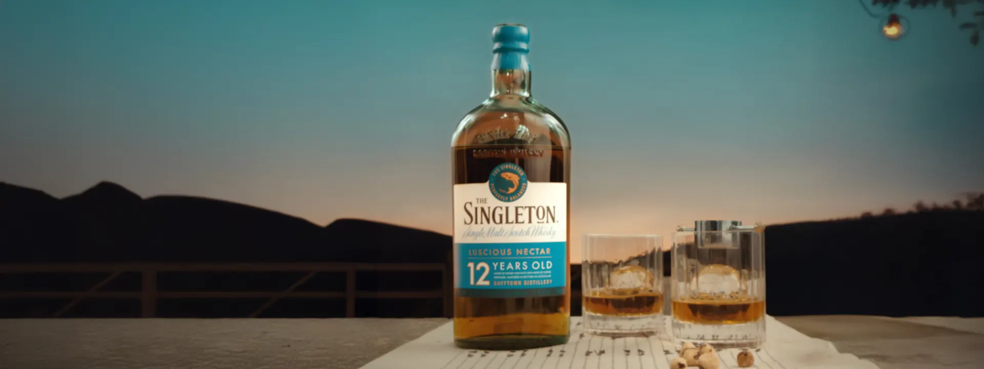 The Singleton 12-Year-Old Luscious Nectar bottle with two whisky glasses against a scenic background