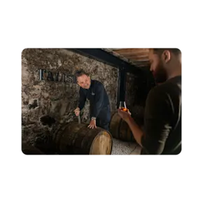 A man taps open a cask and shares a dram of Talisker with a man on the experience.