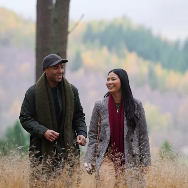 A man and a woman walking through the woods together