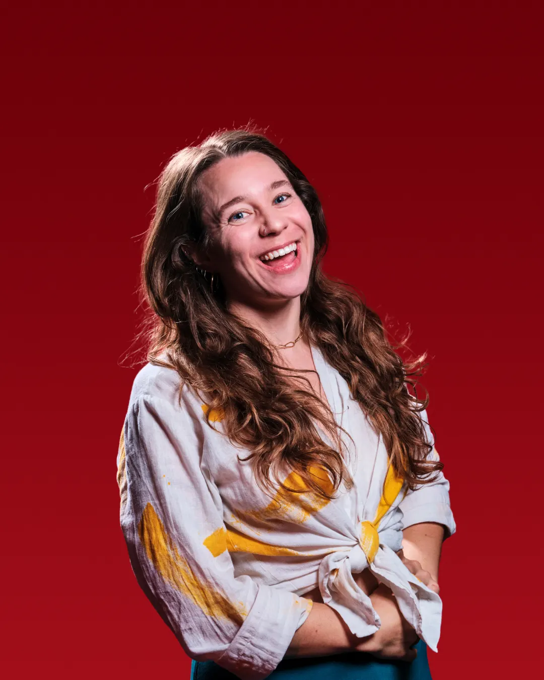 Charlotte Barker stands in front of a red background, smiling at the camera.