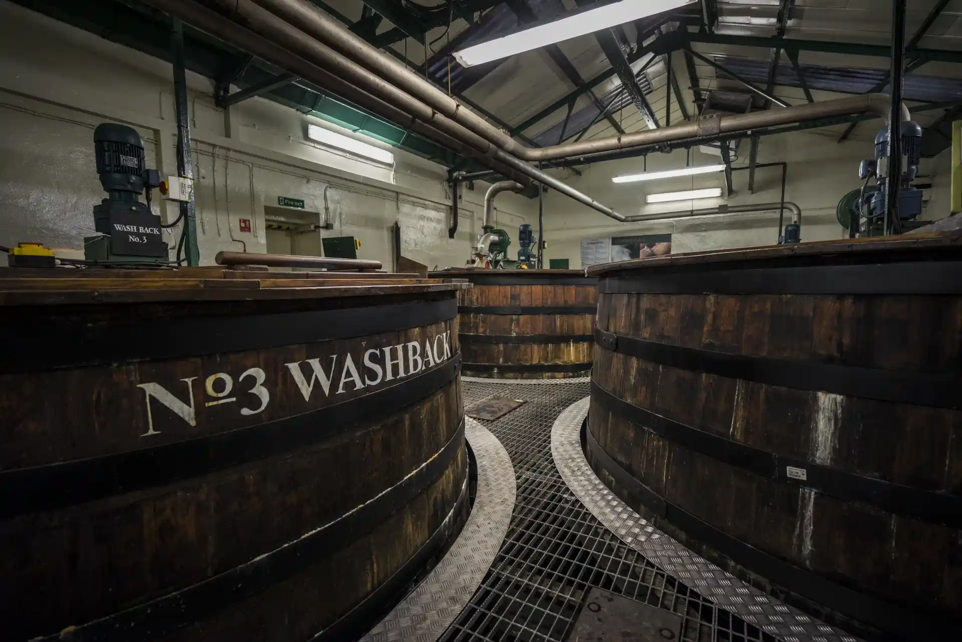 Three wooden whisky washbacks are shown in a production warehouse