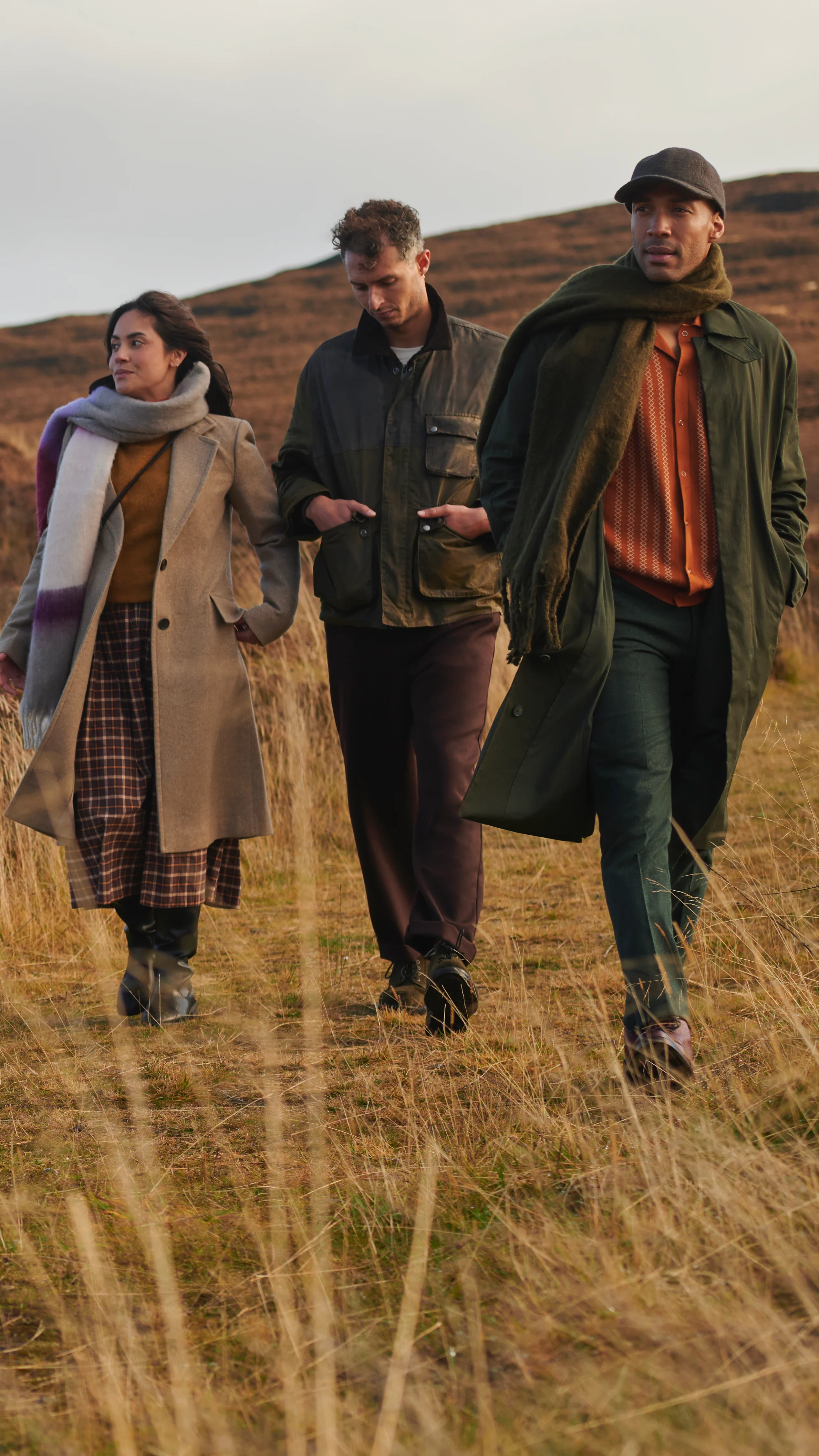 People walking through grassy landscape during a whisky distillery trip in Scotland.