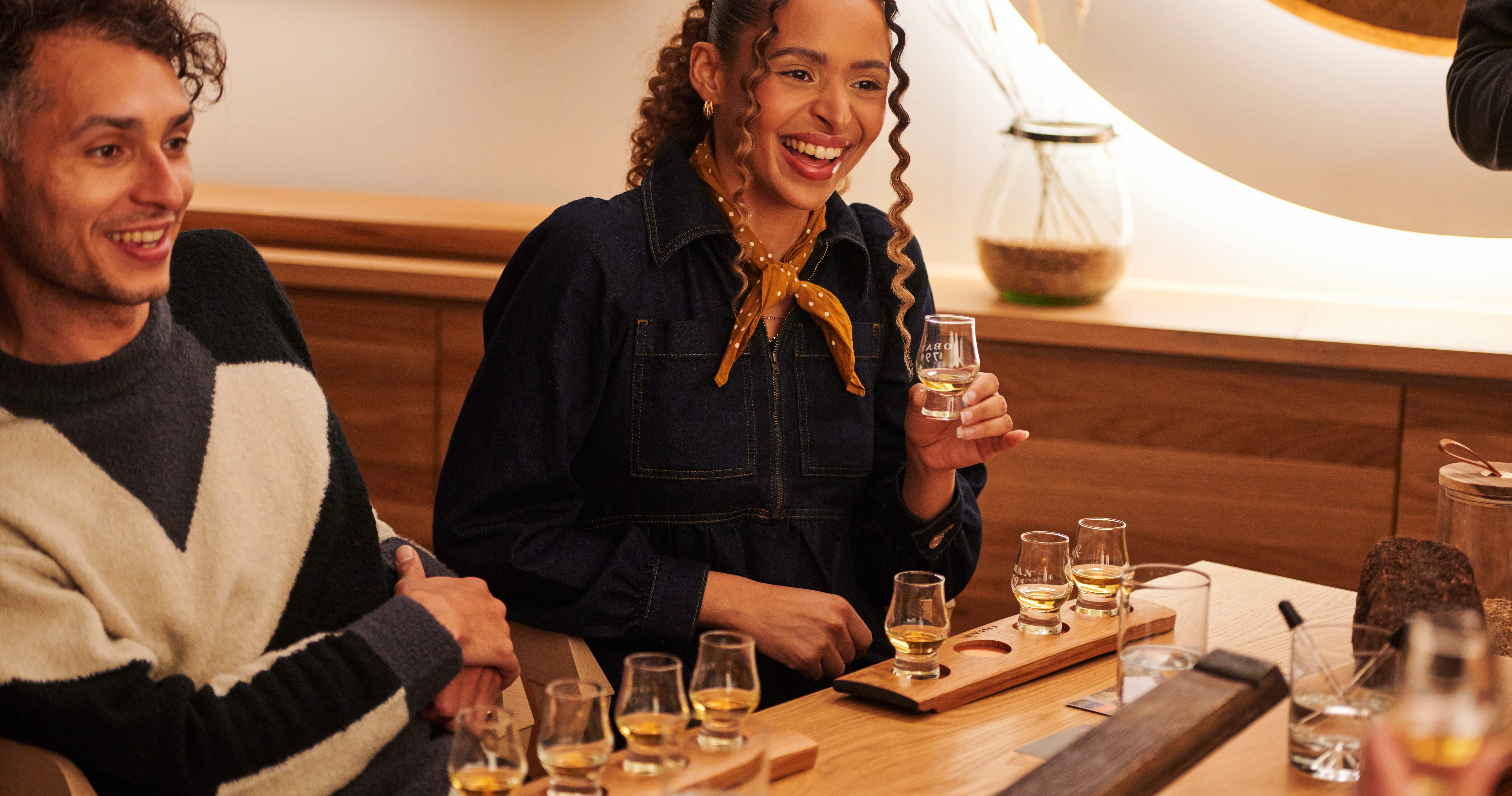 Two friends sit at a table, enjoying a whisky tasting experience at Oban distillery