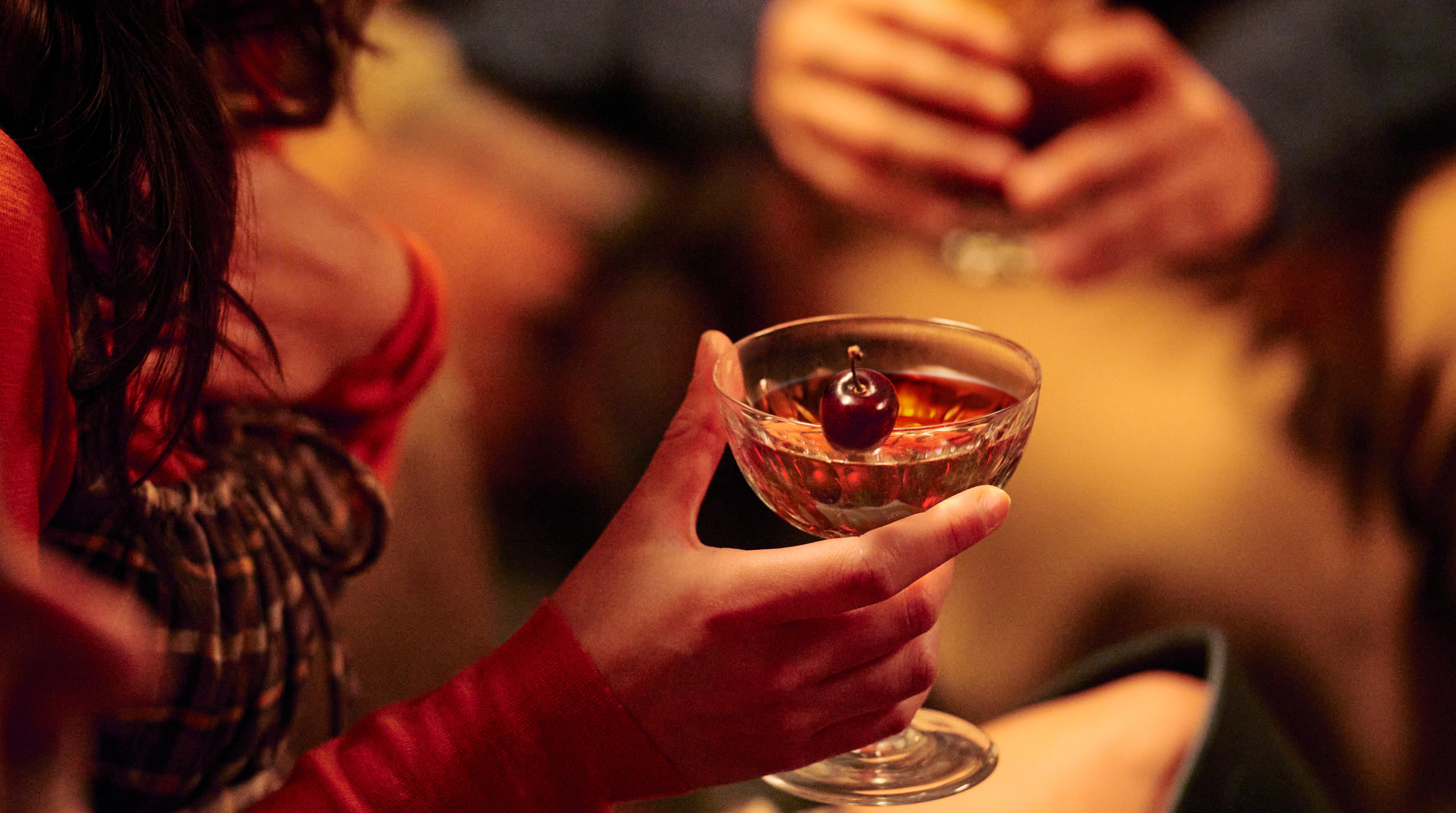 Someone holding a Manhattan cocktail in a coupe 