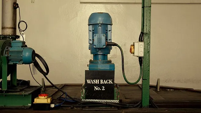 Ein Stück einer alten blauen Brennereimaschine in einem großen Industrieraum.