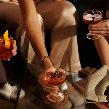 A group of women sit on a sofa enjoying cocktails