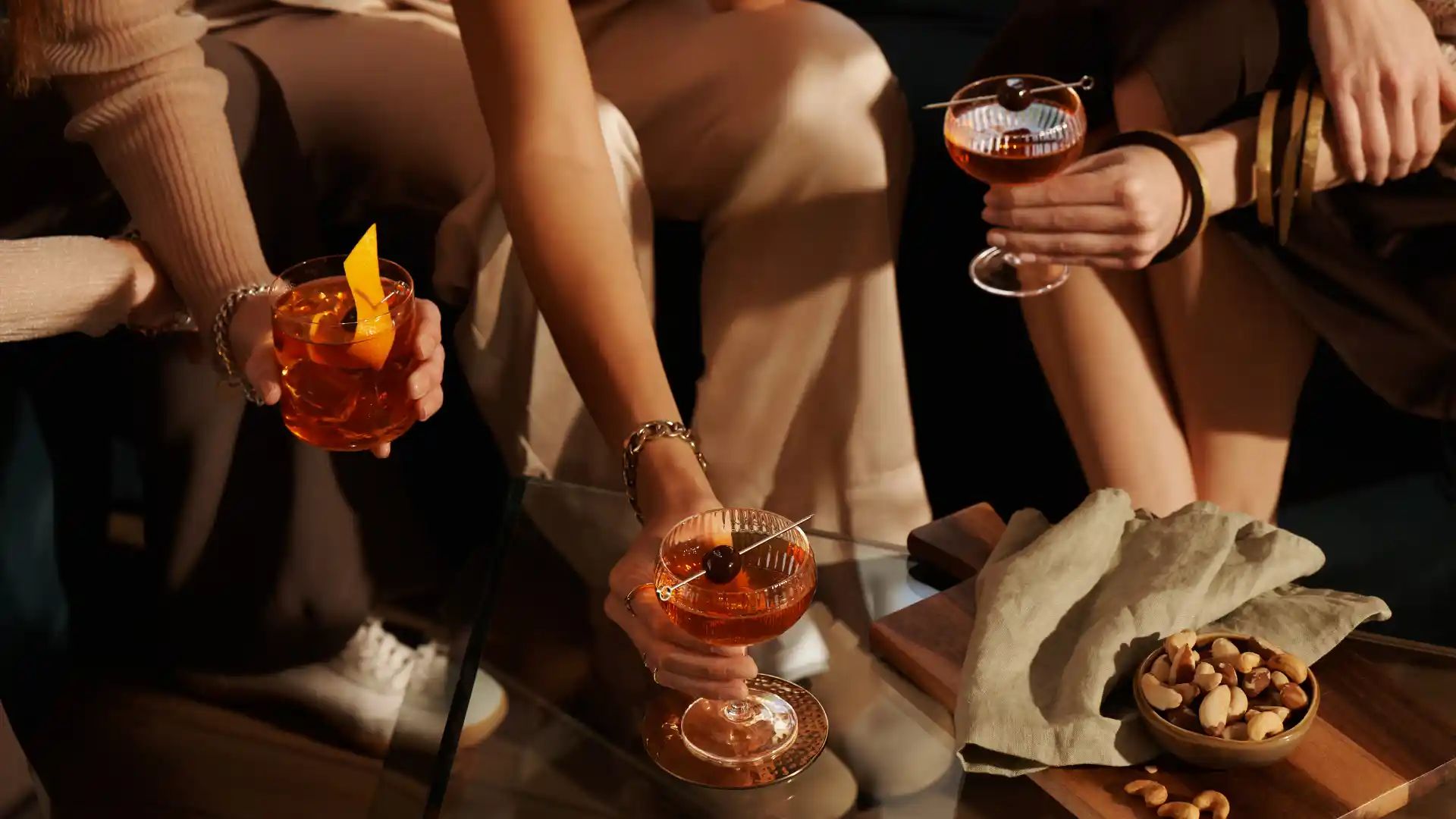 A group of women sit on a sofa enjoying cocktails