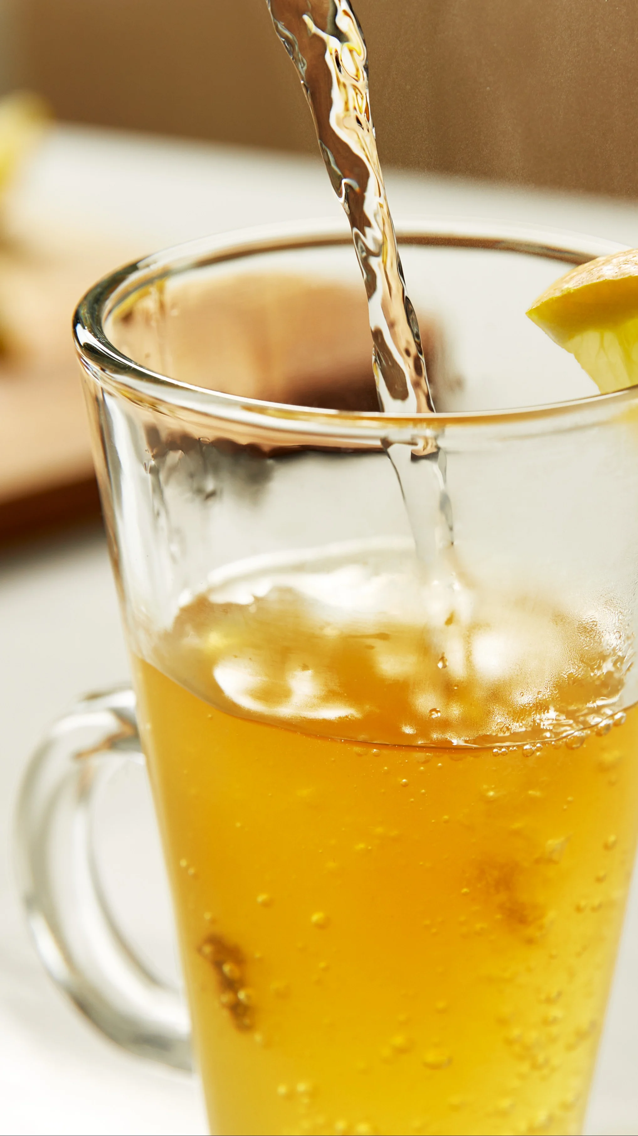 Heißes Wasser wird in ein hitzebeständiges Glas gegossen und mit einer Zitrone garniert