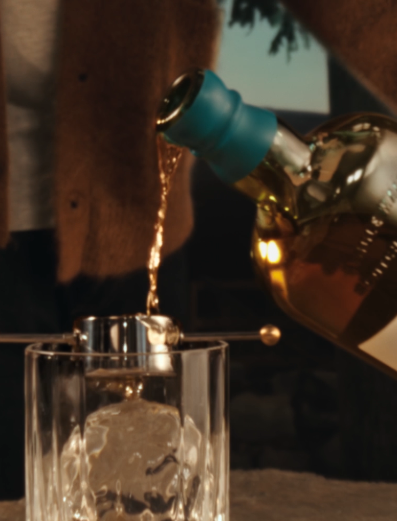 Whisky being poured from a Singleton bottle into a glass with ice
